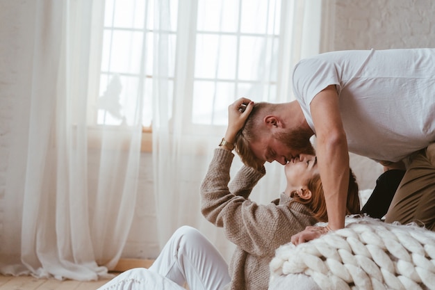 The guy on the bed kisses a woman who sits on the floor