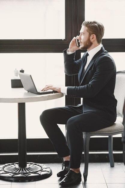 Guy in a black suit. Male at the restaurant. Man with a computer.