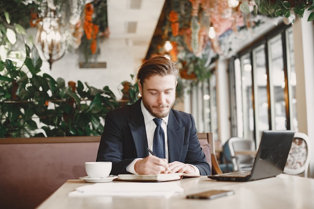 Guy in a black suit. Male at the restaurant. Man with a computer.