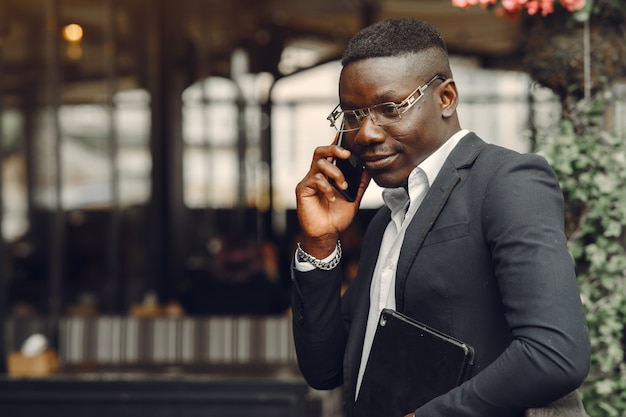 Free photo guy in a black suit. male with a mobile phone. businessman at the office.