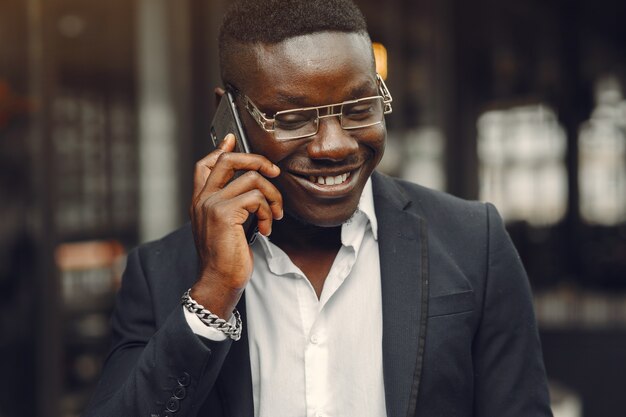 Guy in a black suit. Male with a mobile phone. Businessman at the office.