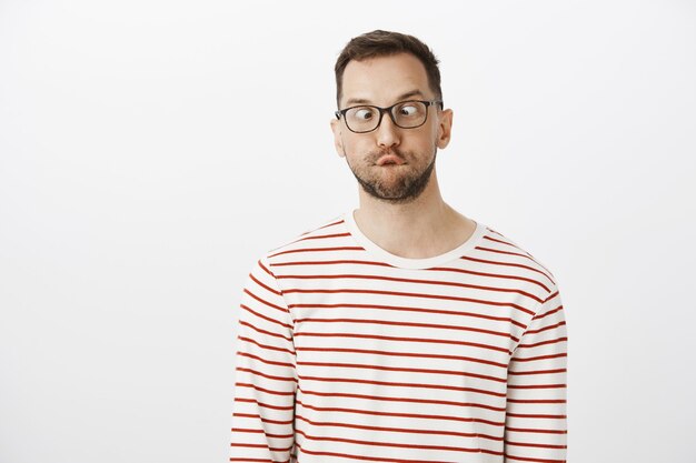 Guy cannot grew up. Portrait of funny playful european man with bristle in glasses, squinting and looking at nose