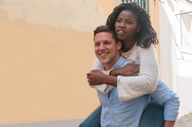 Guy carrying black girlfriend on back in city