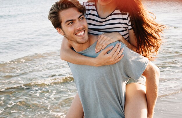 Guy carrying girlfriend at the shoreline close up view