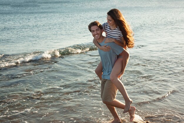 Guy carrying girlfriend at the shoreline
