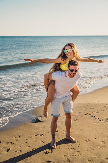 Guy carrying girlfriend at the shoreline