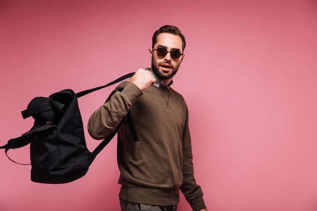 Guy in dark sunglasses wearing backpack on isolated background