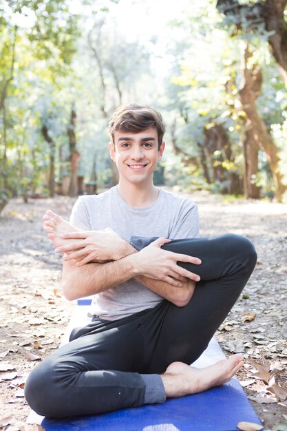 Guy doing yoga exercises on mat outdoors