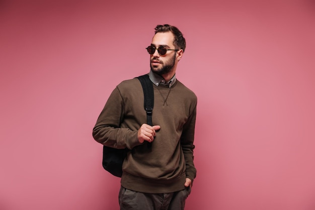 Free photo guy dressed in brown outfit and wearing sunglasses poses with backpack