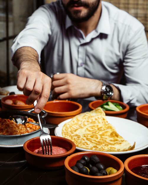 Guy eats breakfast with various food