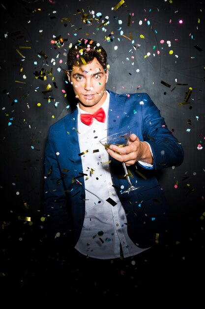 Guy in evening jacket with glass between tossing confetti