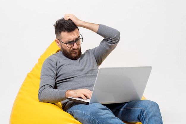 Guy frustrated while sitting on yellow pouf chair