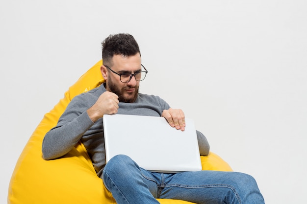 Guy frustrates while sitting on yellow pouf chair