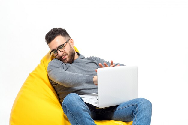 Guy frustrates while sitting on yellow pouf chair