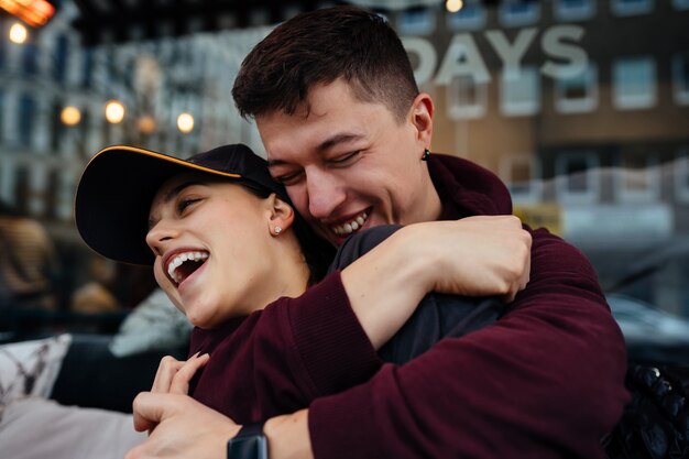 Guy and a girl are hugging at a table in a outdoor cafe.