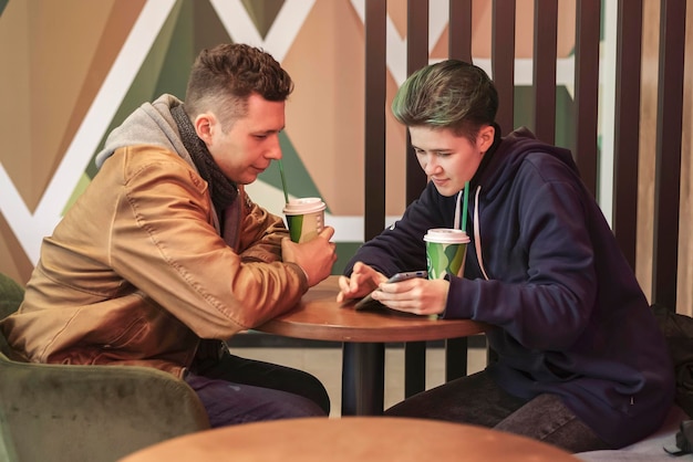 A guy and a girl are sitting in a cafe and using smartphones. communication  technology  internet.