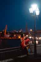 Free photo guy and girl hugging each other on a background of the night port