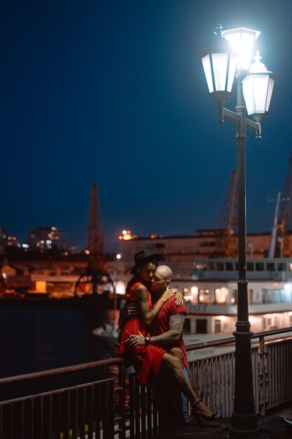 Guy and girl hugging each other on a background of the night port