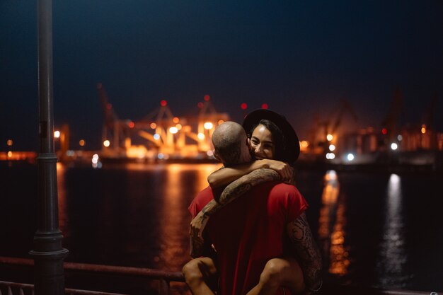 Guy and girl hugging each other on a background of the night port