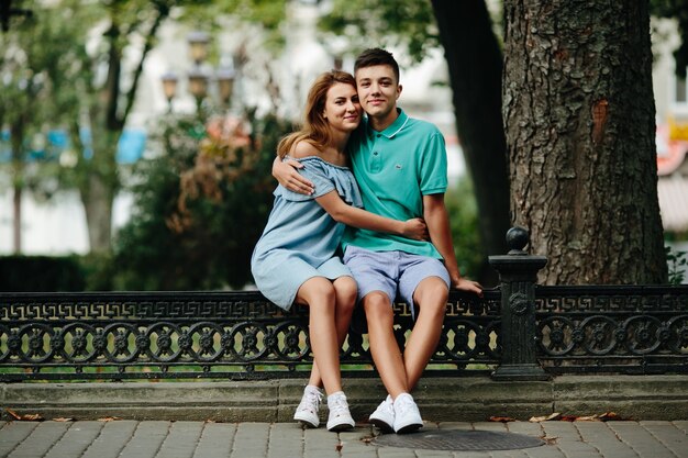 Guy and girl hugging sitting on fence