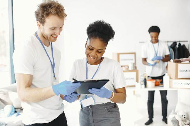 Guy and girl volunteers. Friends in white t-shirts. Humanitarian aid to poor.