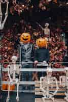 Free photo a guy and a girl with a pumpkin heads posing on the street