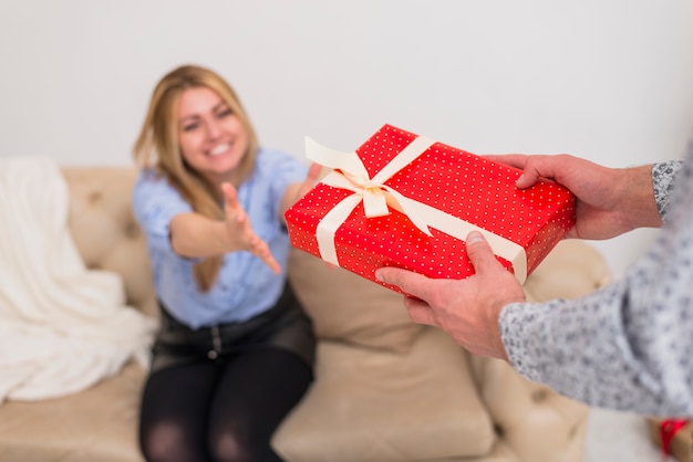 Free photo guy giving present to young smiling lady on settee