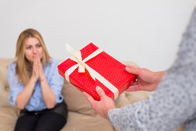 Guy giving present to young surprised lady on settee