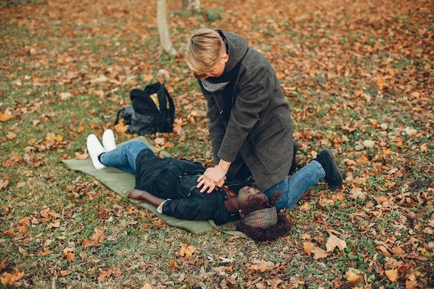 Guy help a woman. African girl is lying unconscious. Providing first aid in the park.