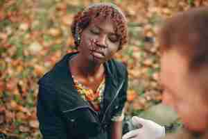 Free photo guy help a woman. african girl sitting unconscious. providing first aid in the park.