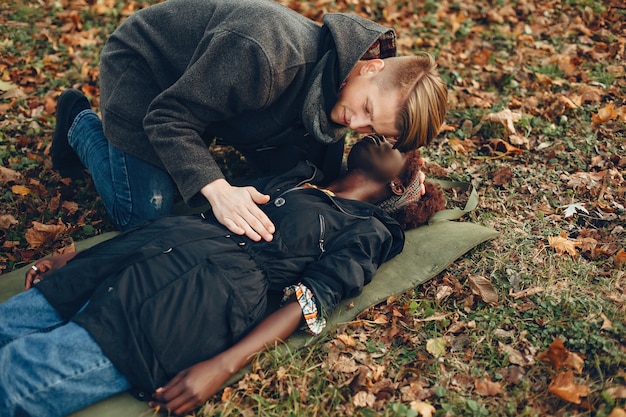 Guy help a woman. Afro girl is lying unconscious. Providing first aid in the park