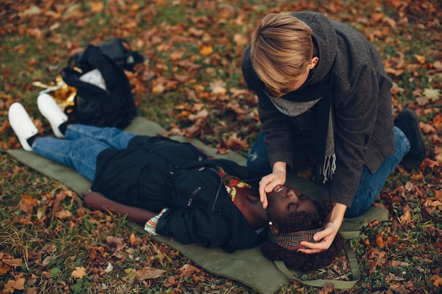 Guy help a woman. Afro girl is lying unconscious. Providing first aid in the park