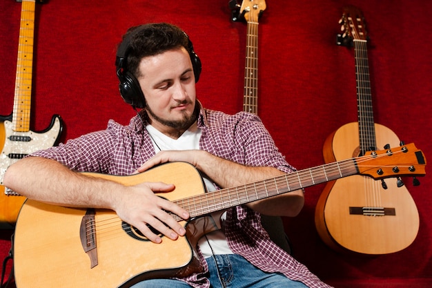 Guy holding an acoustic guitar and looking at the instrument