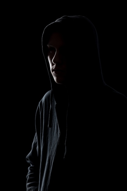 Free photo guy in hooded sweatshirt in the dark