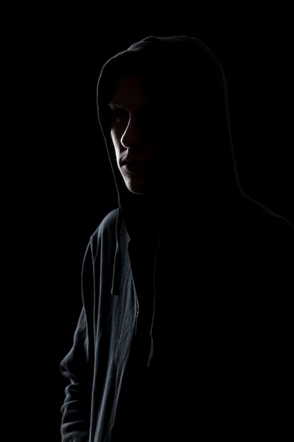 Guy in hooded sweatshirt in the dark