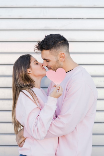 Foto gratuita ragazzo che bacia la signora che tiene simbolo di carta decorativa del cuore