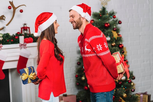 Guy and lady holding presents from backs