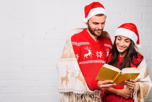 Guy and lady in party hats reading book