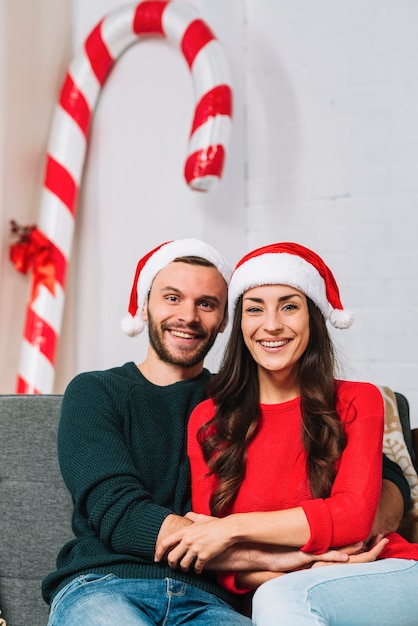 Free photo guy and lady in party hats sitting on sofa