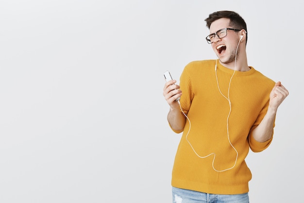 Guy listening music in earphones and singing karaoke app