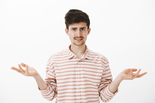 Free photo guy listening ridiculous explanations, being clueless and unimpressed. attractive caucasian brother with moustache and beard, spread palm and shrugging, frowning from misunderstanding, unaware