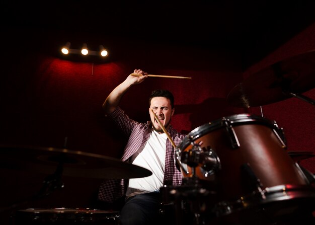 Guy playing drums and stroking with drumsticks