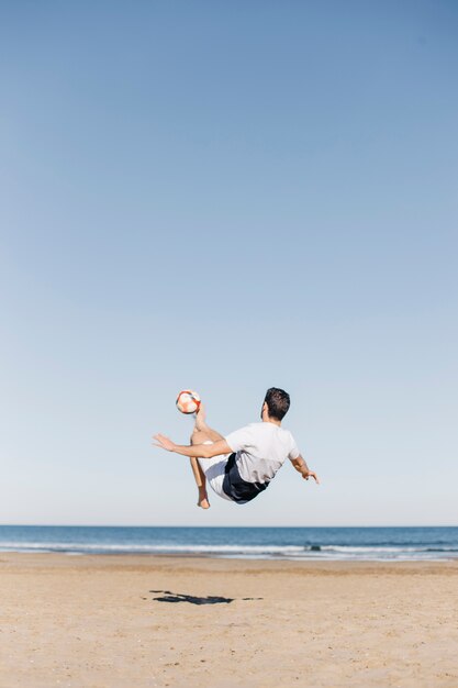 Guy playing football at the beach