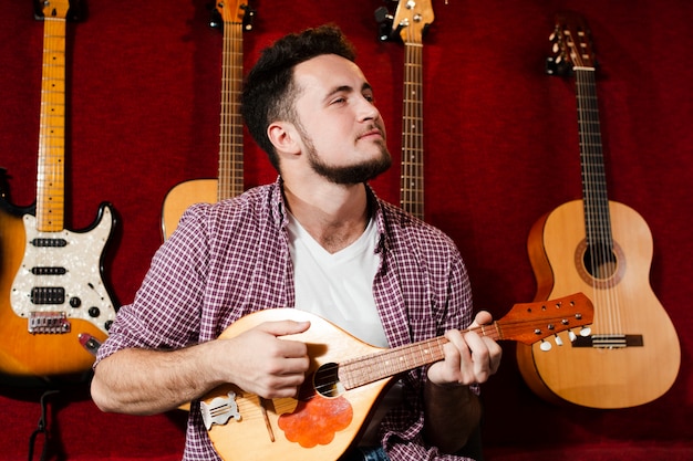 Guy playing at mandolin guitar in the studio