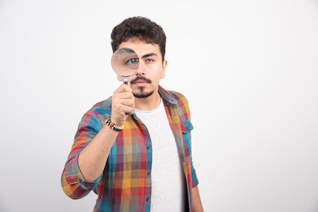 A guy putting a magnifier to his eyes to see bigger.