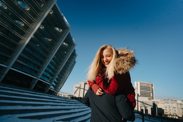 Foto gratuita il ragazzo sulla spalla sta portando la ragazza, l'inverno all'aperto.