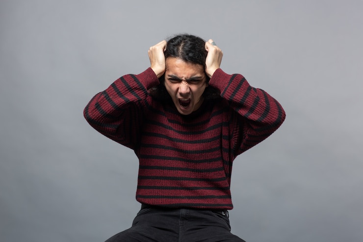 Free Photo a guy shows anger while holding his head