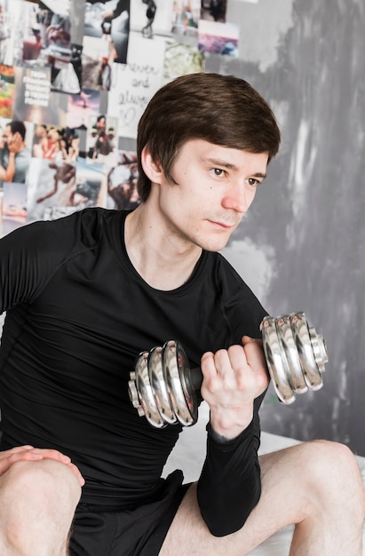 Guy sitting and exercising with dumbbell