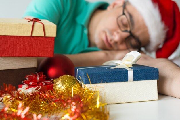 Guy sleeping on table with Christmas gifts and baubles