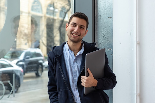 A guy smiles and holds laptop